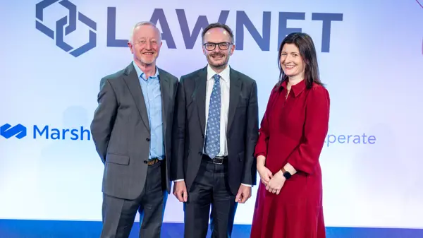 Three people (Chris Marston, Derek Rodgers, Helen Hamilton-Shaw on stage, LawNet logo in background